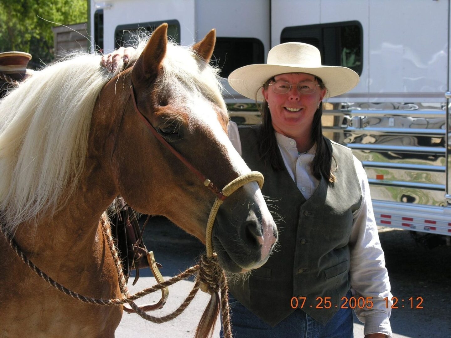 A woman in a cowboy hat standing next to a horse.