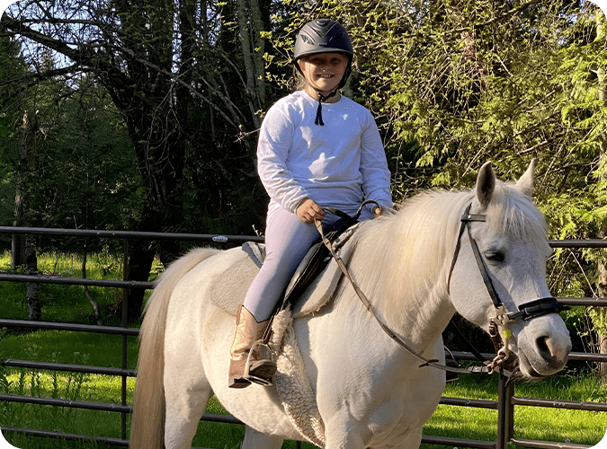 A young girl riding on the back of a white horse.