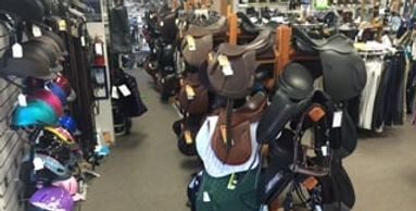 A room filled with lots of saddles and horses.